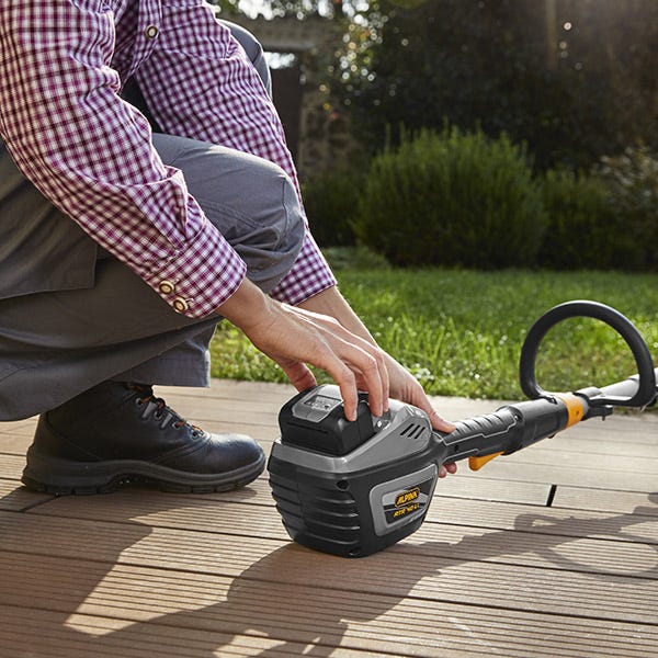 Femme branche la batterie dans un outil de jardin Alpina 40V